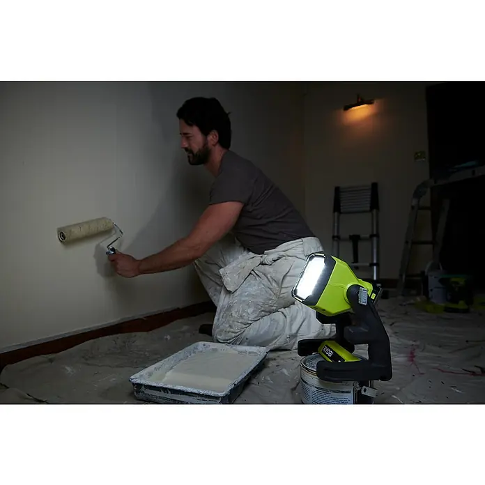 Ryobi ONE+ LED-Akkustrahler RLFD18-0 - 18 V, Ohne Akku, 1.800 lm - Maler bei der Arbeit mit einer hellen RYOBI-Arbeitsleuchte, die den Raum gut ausleuchtet.