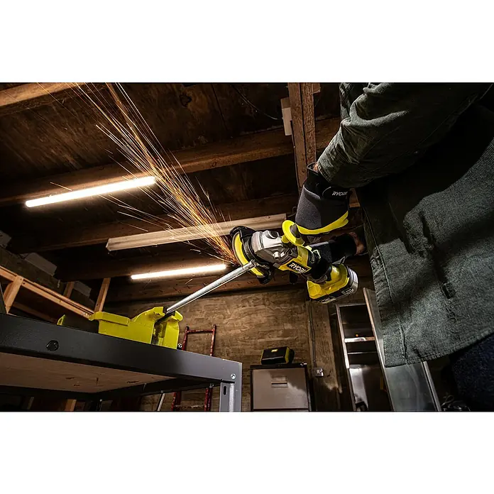 Ryobi ONE+HP Akku-Winkelschleifer RAG18X-0 Performance - Ohne Akku, Durchmesser Scheibe: 125 mm - Die Ryobi-Flex schleift Metall und erzeugt dabei viele Funken. Die Arbeit wird in einer Werkstatt an einem Schraubstock durchgeführt.