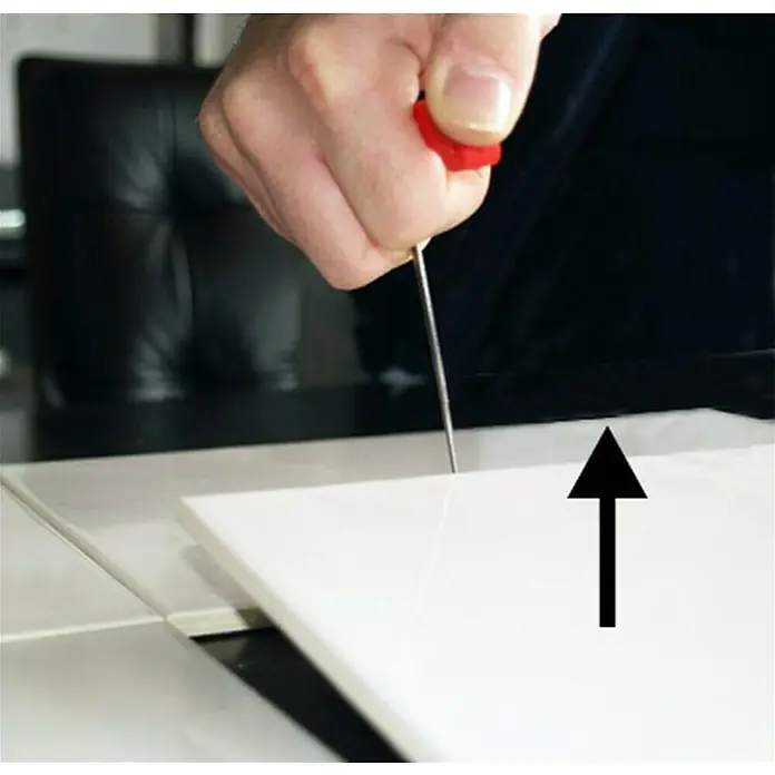 Heka Plattenheber - Plattenstärke: 0 mm - 70 mm - Nahaufnahme einer Hand, die ein Werkzeug zum Anheben einer weißen Fliese auf einem Tisch benutzt.
