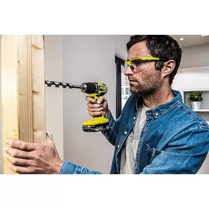 Ryobi ONE+HP Akku-Bohrschrauber RDD18C-0 - 18 V, Ohne Akku, 54 Nm - Ein Mann nutzt einen gelb-schwarzen Ryobi Bohrer mit einem großen Holzbohrer, um in einen Holzbalken zu bohren.