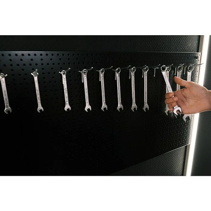 Brüder Mannesmann Ringmaulschlüssel-Satz - Schlüsselweite: 6 mm - 22 mm - Werkzeugwand mit verschiedenen Schraubenschlüsseln, einer wird von einer Hand abgenommen. Praktische Werkstattausrüstung.