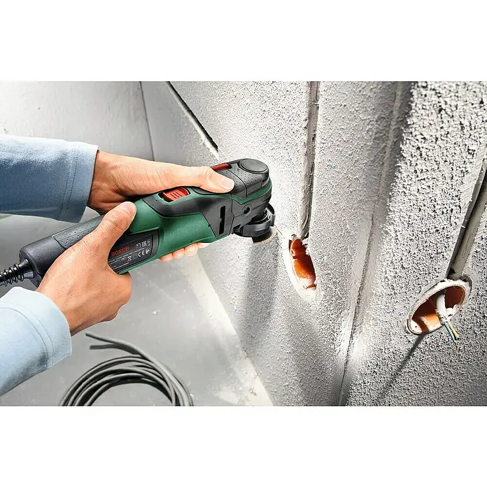Bosch Elektro-Multifunktionswerkzeug PMF 350 CES - 350 W, STARLOCK-System - Ein Mann verwendet ein Bosch Multifunktionswerkzeug, um präzise Ausschnitte in einer verputzten Wand für elektrische Installationen zu machen.