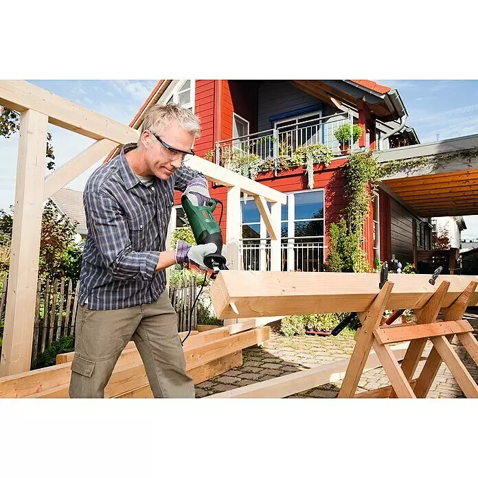 Bosch Säbelsäge PSA 900 E - 900 W, Hublänge: 28 mm, 2 Sägeblätter - Mann sägt draußen mit einer grünen Bosch-Säbelsäge einen Holzbalken.