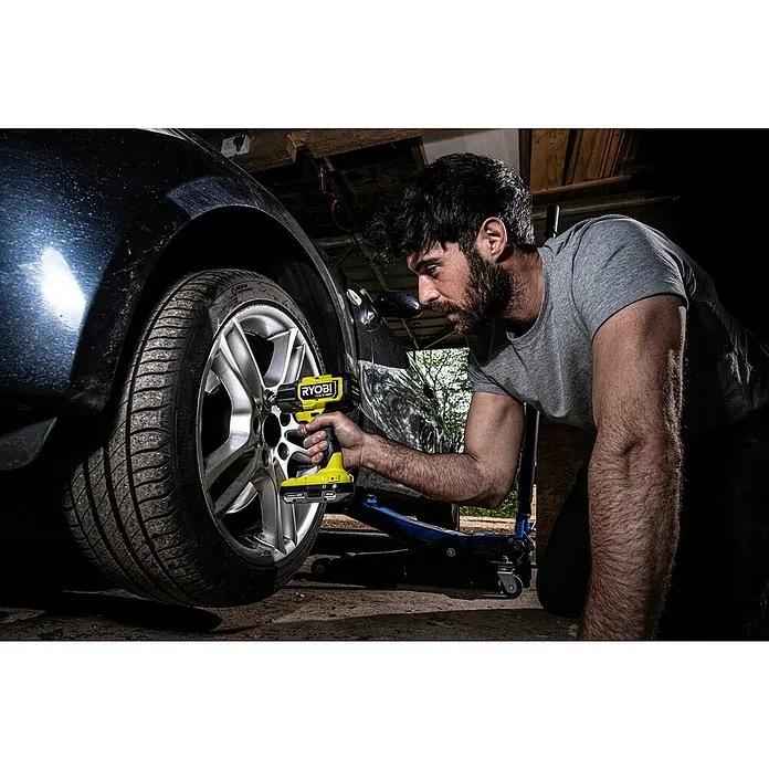Ryobi ONE+HP Akku-Schlagschrauber RIW18X-0 Performance - 18 V, Ohne Akku, Leerlaufdrehzahl: 0 U/min - 2.800 U/min - Ein Mann benutzt einen gelben RYOBI-Schlagschrauber, um an einem Auto zu arbeiten. Das Werkzeug ist gut sichtbar.