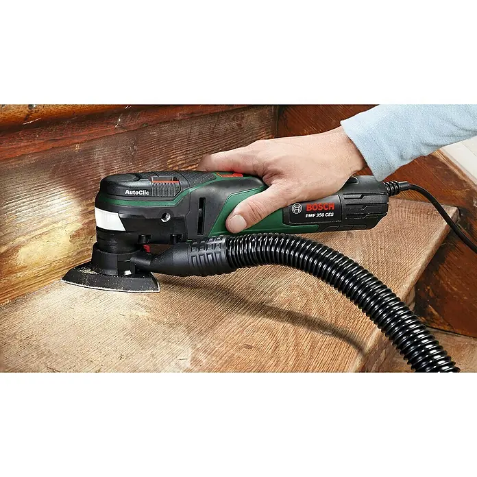 Bosch Elektro-Multifunktionswerkzeug PMF 350 CES - 350 W, STARLOCK-System - Nahaufnahme eines Bosch PME 350 CES Multifunktionswerkzeugs beim Schleifen einer Holzoberfläche mit Staubsaugeranschluss.