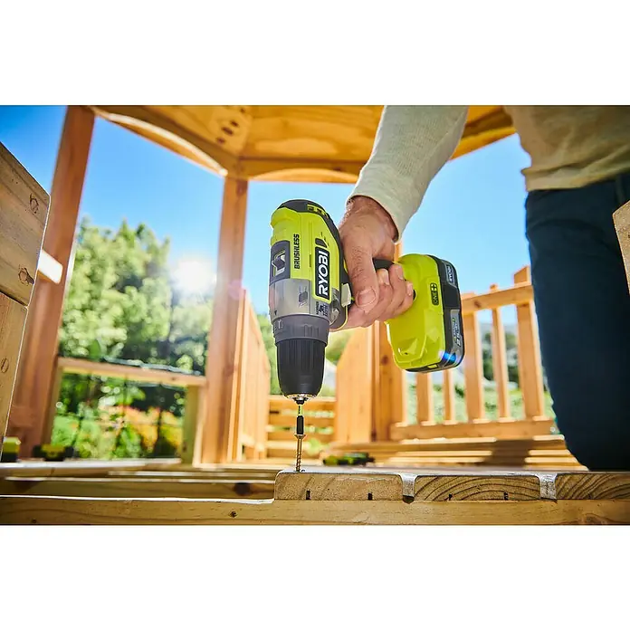 Ryobi ONE+ Akku-Schlagbohrschrauber R18PD5-0 - 18 V, Ohne Akku, 50 Nm - Nahaufnahme eines Ryobi Akku-Bohrschraubers, der eine Schraube in ein Holzbrett dreht. Ideal für Heimwerkerprojekte im Freien.