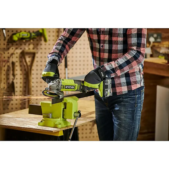 Ryobi ONE+ Akku-Winkelschleifer RAG18125-0 - Ohne Akku, Durchmesser Scheibe: 125 mm - Ein Mann benutzt einen Ryobi Winkelschleifer mit Akku in einer Werkstatt, um ein Metallstück zu bearbeiten, während er Schutzkleidung trägt.