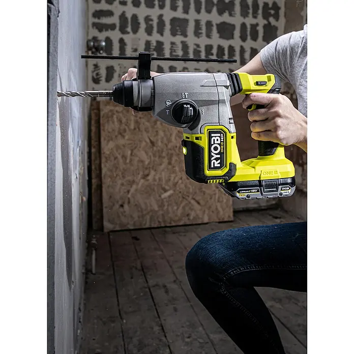Ryobi ONE+HP Akku-Kombihammer RSDS18X-0 - 18 V, Ohne Akku, 2,5 J - Ein Mann bohrt mit einem gelb-grauen Ryobi-Bohrhammer ein Loch in eine Wand, wobei der Bohrer im Einsatz ist.
