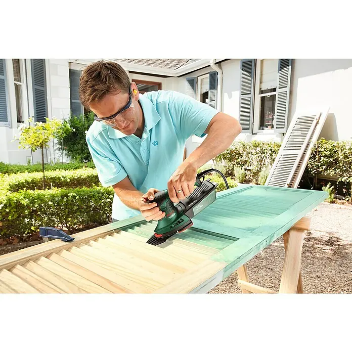 Bosch Elektro-Multischleifer PSM 200 AES - 200 W, Leerlaufschwingzahl: 6.000 U/min - 26.000 U/min, Durchmesser Schwingkreis: 1,8 mm - Ein Mann schleift mit einem Bosch-Multischleifer eine Fensterläden. Der Multischleifer eignet sich perfekt zum Renovieren von Möbeln.