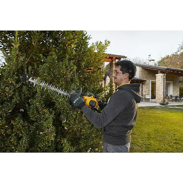 Stiga Benzin-Heckenschere HT 525 - 0,65 kW, Schnittlänge: 46 cm, Max. Aststärke: 27 mm - Mann, der mit einer STIGA-Heckenschere eine Hecke schneidet.