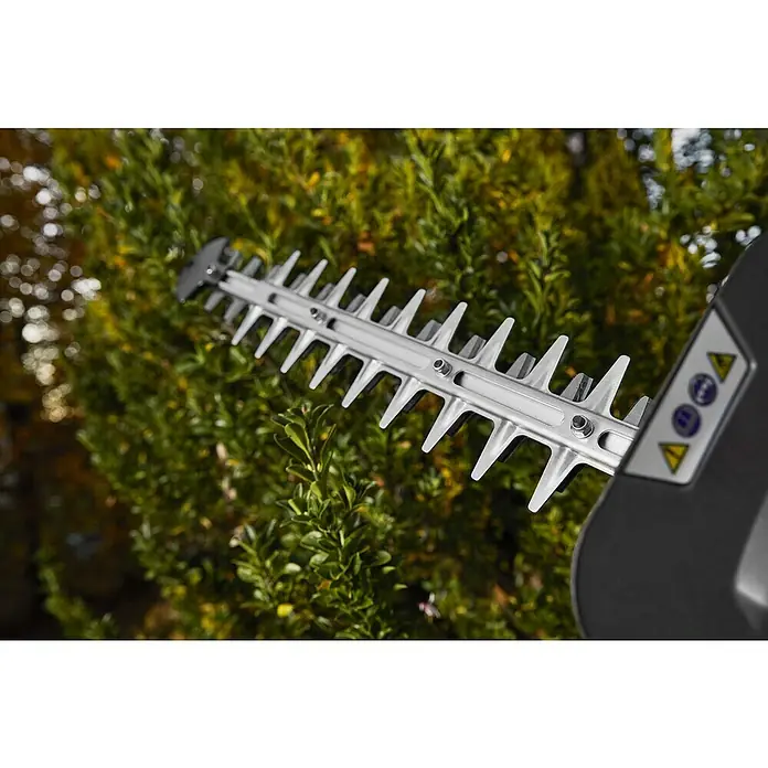 Stiga Benzin-Heckenschere HT 525 - 0,65 kW, Schnittlänge: 46 cm, Max. Aststärke: 27 mm - Nahaufnahme einer Heckenschere, die bereit ist, einen grünen Busch zu schneiden, wobei der Fokus auf den scharfen, silbernen Klingen liegt.