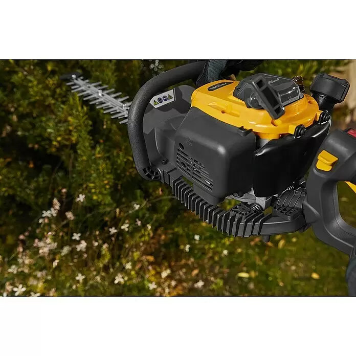 Stiga Benzin-Heckenschere HT 525 - 0,65 kW, Schnittlänge: 46 cm, Max. Aststärke: 27 mm - Eine Person mit Handschuhen bedient eine schwarz-gelbe Heckenschere mit silbernen Klingen.