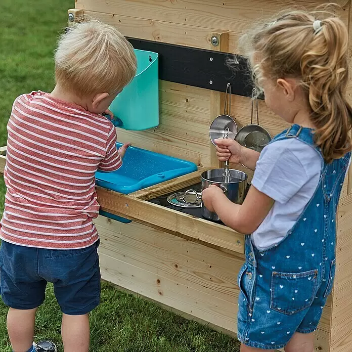TP Toys Matschküche - 36 x 81 x 56 cm, Holz - Zwei Kinder spielen mit einer hölzernen Matschküche im Freien, ausgestattet mit Spüle und Spielutensilien.