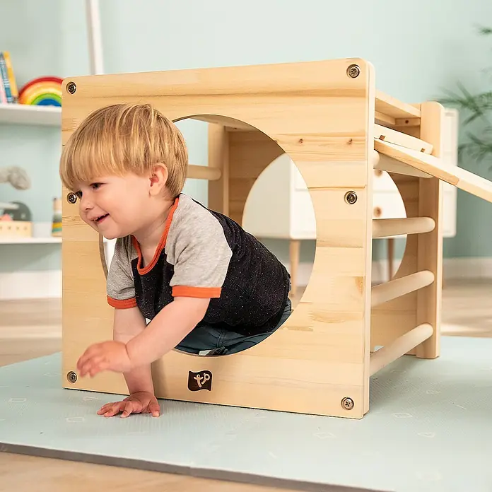 TP Toys Klettergerüst Active Tots Cube - 62 x 60 x 52 cm, Holz, Natur - Ein Kleinkind klettert durch einen Spielwürfel aus Holz, der mit Sprossen und einem Loch zum Durchkriechen versehen ist.