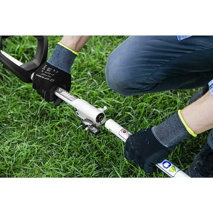 Stiga Benzin-Motorsense GT 330 A - 700 W, Schnittbreite Faden: 38 cm - Eine Nahaufnahme eines STIGA-Rasentrimmers, der von einer Person in Arbeitskleidung zusammengebaut wird.