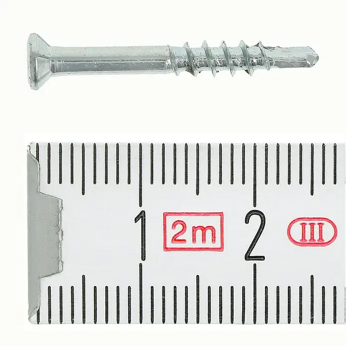 Profi Depot Dielenschraube VZ TX - Durchmesser: 3,2 mm, Länge: 25 mm, TX für TORX-Antriebe, 200 Stk. - Schraube neben einem Messgerät. Die Schraube ist silberfarben und hat einen flachen Kopf und ein scharfes Gewinde.