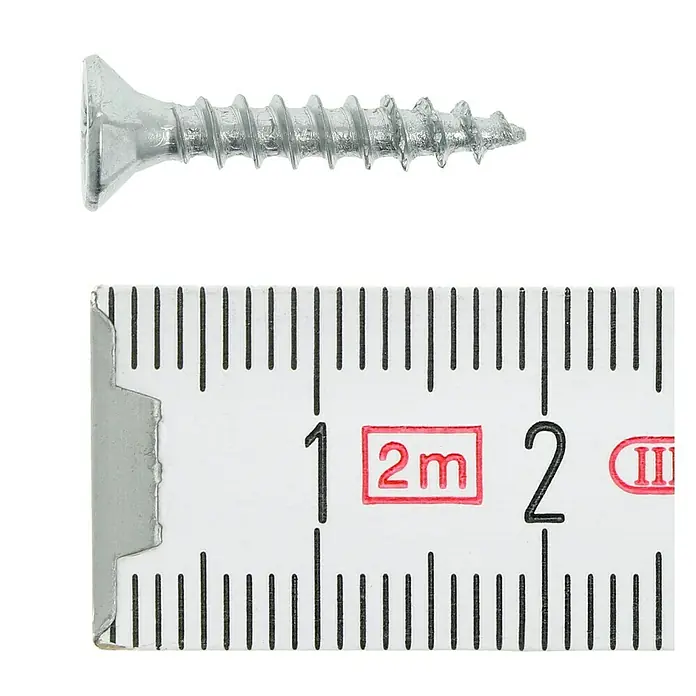 Profi Depot Tornillo para madera - Ø x L: 3,5 x 20 mm, 200 ud., Zincado, Ranura en forma de cruz Pozidriv - Primer plano de un tornillo con una regla de medición para comparar tamaños.