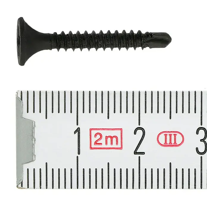 Profi Depot SchnellbauschraubeDurchmesser: 3,5 mm, Länge: 25 mm, Senkkopf, Mit Bohrspitze, 1.000 Stk. - Nahaufnahme einer schwarzen Bohrschraube neben einem Messlineal, das etwa 2,8 cm anzeigt. Die Schraube liegt horizontal und ist scharf abgebildet.