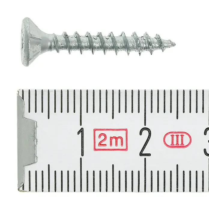 Profi Depot Tornillo para madera - Ø x L: 4 x 25 mm, 200 ud., Zincado, Ranura en forma de cruz Pozidriv - Primer plano de un tornillo para madera de color plateado junto a una regla para determinar su tamaño.