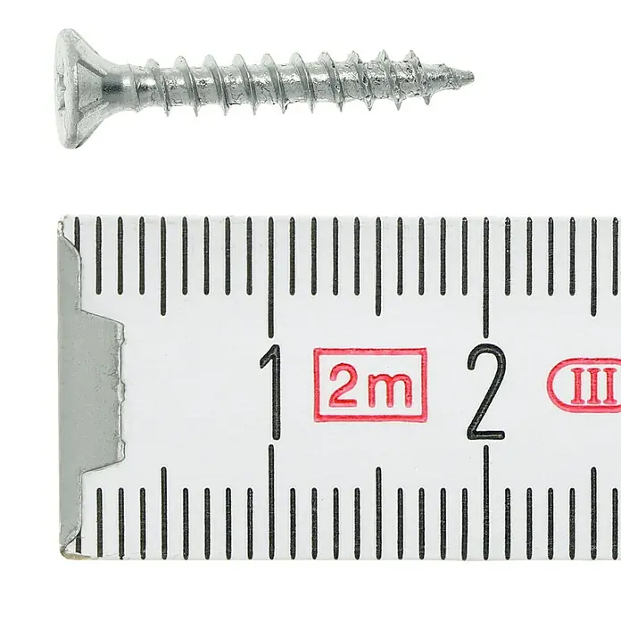 Profi Depot Tornillo para madera - Ø x L: 3 x 20 mm, 1.000 ud., Zincado, Ranura en forma de cruz Pozidriv - Primer plano de un tornillo junto a una regla para medir el tamaño. La imagen muestra el diseño detallado del tornillo.