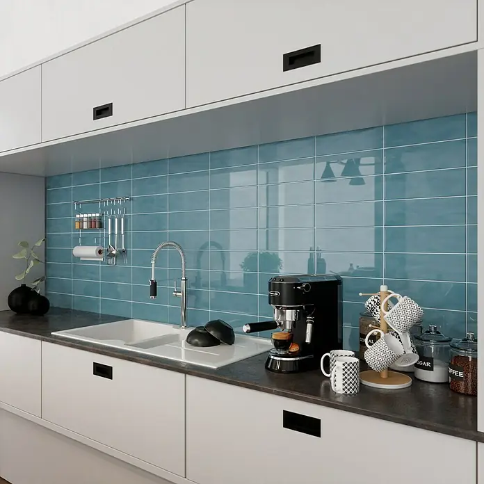 Modern Style Wandfliese Emotion Azul 730 - 9,8 x 29,8 cm, Blau, Glänzend - Küchenspüle mit Armatur, Kaffeemaschine und Tassen auf einer dunklen Arbeitsplatte vor blaugrünem Fliesenspiegel.