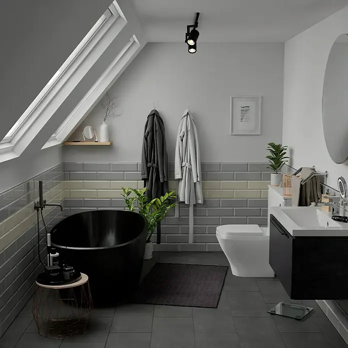 Modern Style Wandfliese Manhattan Biselado Cinze 600 - 9,8 x 29,8 cm, Grau, Glänzend - Elegantes Badezimmer mit freistehender Badewanne, grauen Fliesen und Dachfenstern. Die schwarze Wanne ist ein echter Hingucker.