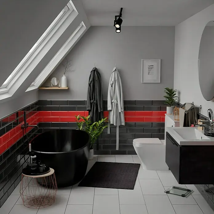 Modern Style Wandfliese Manhattan Biselado Cince 670 - 9,8 x 29,8 cm, Anthrazit, Glänzend - Badezimmer mit freistehender Badewanne, WC und Waschtisch. Das moderne Design wird durch die roten Akzente hervorgehoben.