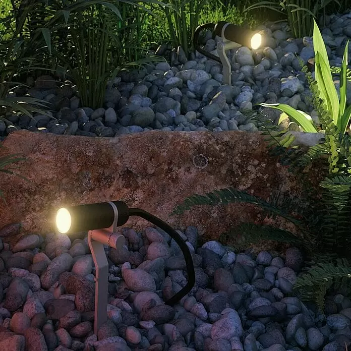 Paulmann Plug & Shine LED-Gartenspot Plantini - 2 W, Erdspieß, Höhe: 22,3 cm, 24 V - Zwei schwarze und silberne Gartenstrahler beleuchten ein Steinbeet mit Pflanzen und schaffen stimmungsvolles Licht.