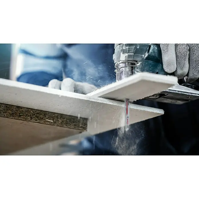 Bosch Expert Säbelsägeblatt Fiber Plaster T141 HM - Länge: 100 mm - Detailaufnahme einer Stichsäge beim Schneiden eines Werkstücks, Späne fliegen. Der Handwerker trägt Schutzhandschuhe.