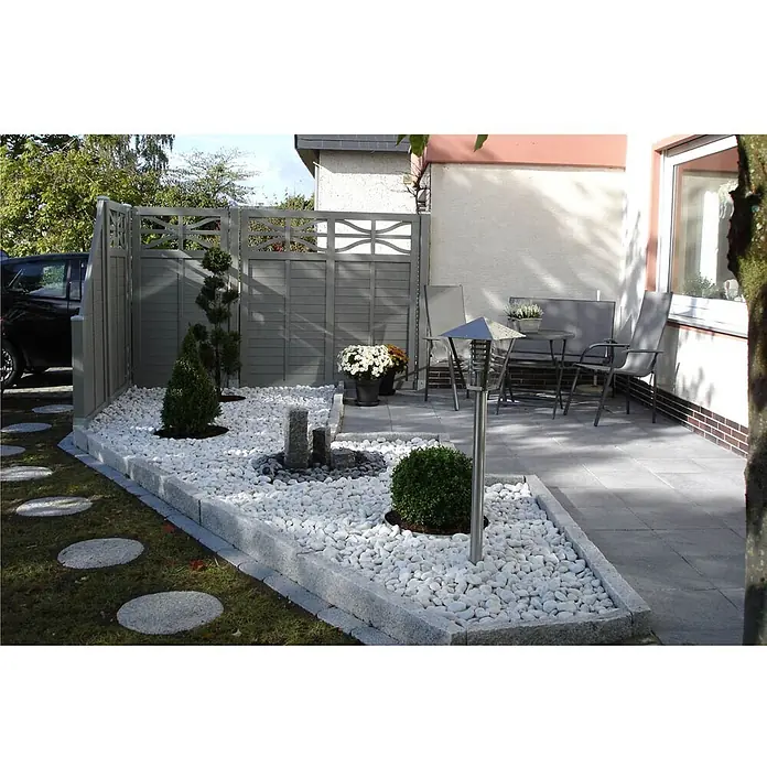 Min2C Marmorkiesel - Weiß, Körnung: 60 mm - 100 mm, 25 kg - Gartengestaltung mit weißem Kies, Zierpflanzen und einer grauen Zaunanlage, die einen modernen und stilvollen Außenbereich schafft.
