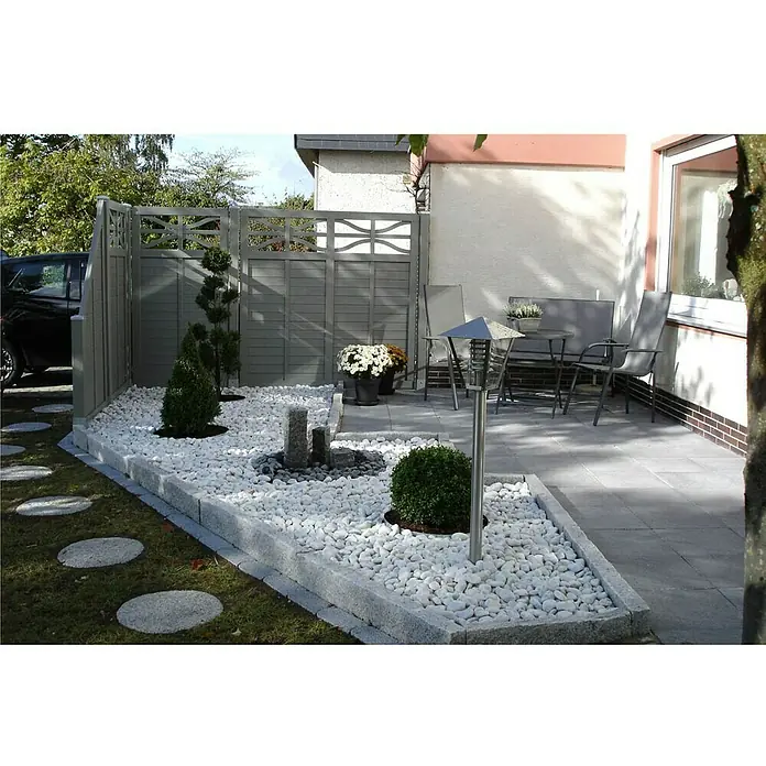 Min2C Marmorkiesel - Weiß, Körnung: 60 mm - 100 mm, 25 kg - Gartengestaltung mit weißem Kies, Zierpflanzen und einer grauen Zaunanlage, die einen modernen und stilvollen Außenbereich schafft.