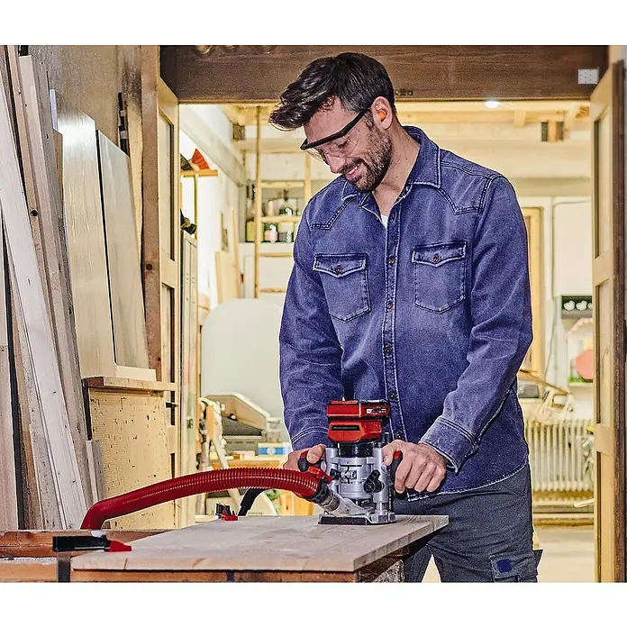 Einhell Professional PXC 18V Fresadora combinada de batería TP-RO 18 Set Li BL - 18 V, Sin batería - Un hombre usa una fresadora inalámbrica Einhell en una mesa de madera en su taller para realizar trabajos de carpintería precisos.