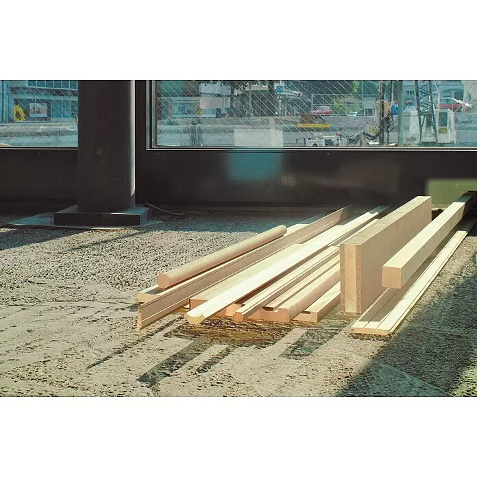 Bosch Kreissägeblatt Optiline Wood - 254 mm, Bohrung: 30 mm, Anzahl Zähne: 24 Stk. - Helle Holzbretter und -leisten in verschiedenen Formen, auf einem Baustellenboden gestapelt.
