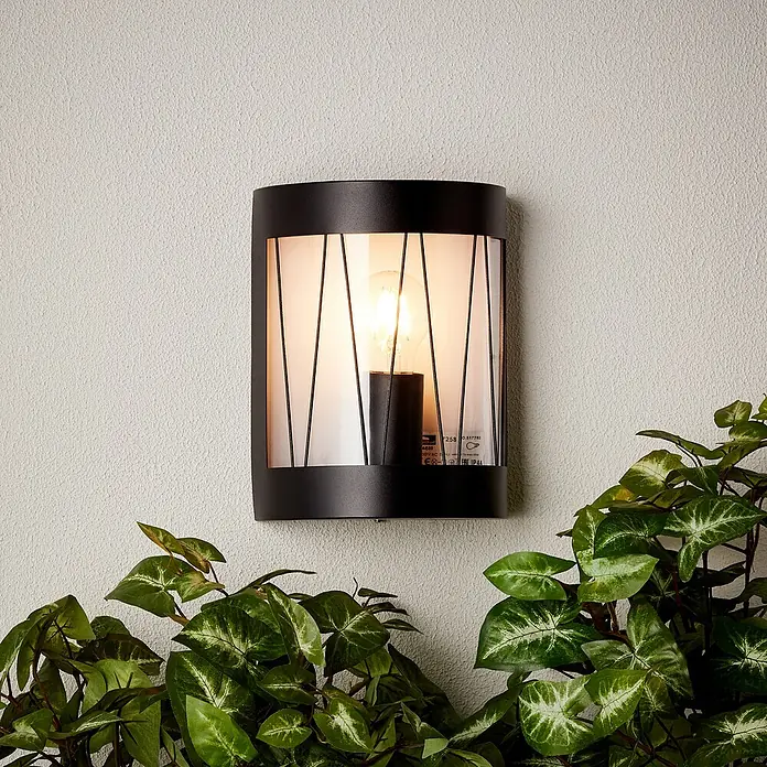 Brilliant Reed Außenwandleuchte - 40 W, 10,5 x 18,2 x 23,6 cm, Schwarz matt, IP44 - Moderne schwarze Wandleuchte mit klarem Schirm und warmem Licht, umgeben von üppigem Grün. Eine stilvolle Ergänzung für jeden Außenbereich.