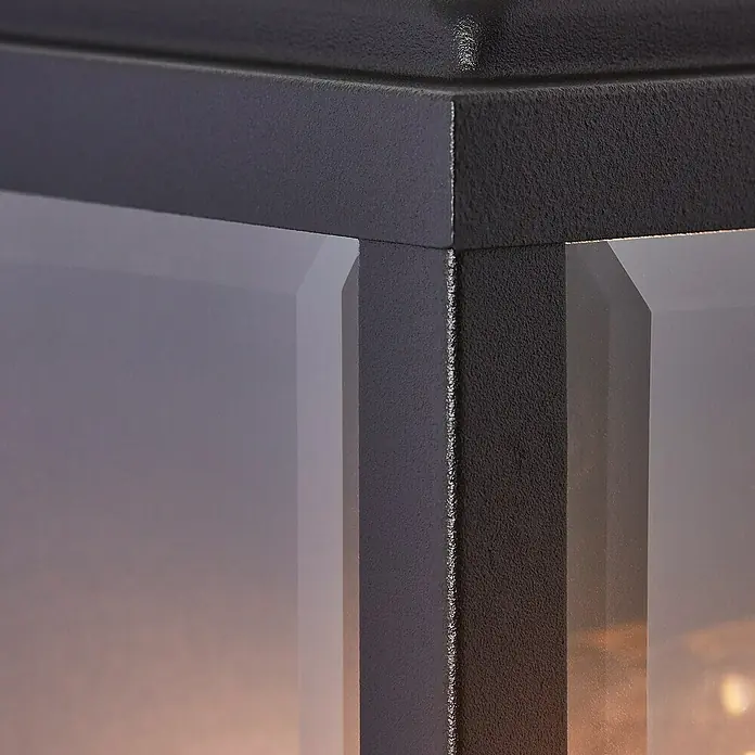 Brilliant Außenwandleuchte Gaia - 60 W, 12 x 16 x 25 cm, Schwarz, IP44 - Nahaufnahme einer eleganten schwarzen Metalllaterne mit präzisen Kanten und klaren Glasscheiben, die ein modernes Designelement hervorheben.