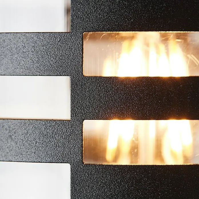 Brilliant Venlo Außenwandleuchte - 40 W, Ø x H: 12,7 x 30,5 cm, Schwarz matt, IP44 - Nahaufnahme einer modernen Wandleuchte mit rechteckigen Ausschnitten und warmem Lichtschein.