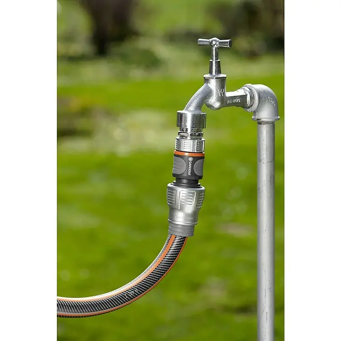 Gardena Schlauchkupplung - Größe: ¾″, Ohne Wasserstopp - Nahaufnahme einer Gardena Schlauchkupplung, die an einem Wasserhahn im Freien befestigt ist, ideal für die Gartenbewässerung.