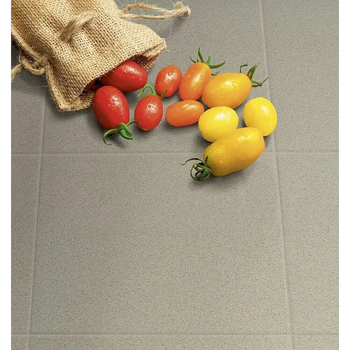 Feinsteinzeugfliese Cefalu - 30 x 30 cm, Grau, Matt - Ein rustikaler Jutesack liegt auf grauem Fliesengrund, aus dem bunte Kirschtomaten in Rot, Gelb und Orange hervorquellen.