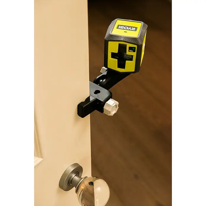 Ryobi Kreuzlinienlaser RBCLLG1 - Max. Arbeitsbereich: 15 m - Nahaufnahme eines Ryobi-Kreuzlinienlasers, der mit einer Klemme an einer Tür befestigt ist, ideal für präzise Ausrichtung bei Bauprojekten.