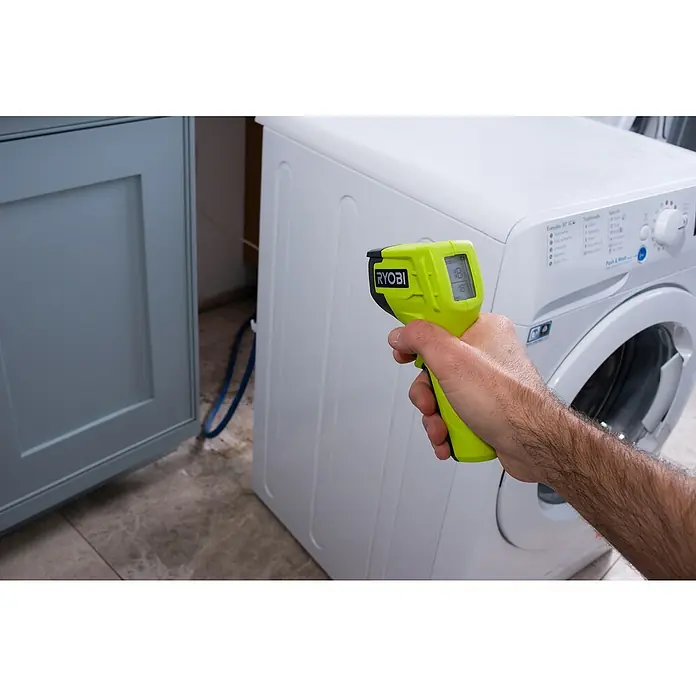 Ryobi Infrarot-Thermometer RBIRT08 - Messbereich: -50 °C bis +500 °C - Nahaufnahme eines Ryobi-Thermometers, das die Temperatur einer weißen Waschmaschine in einem Badezimmer misst.