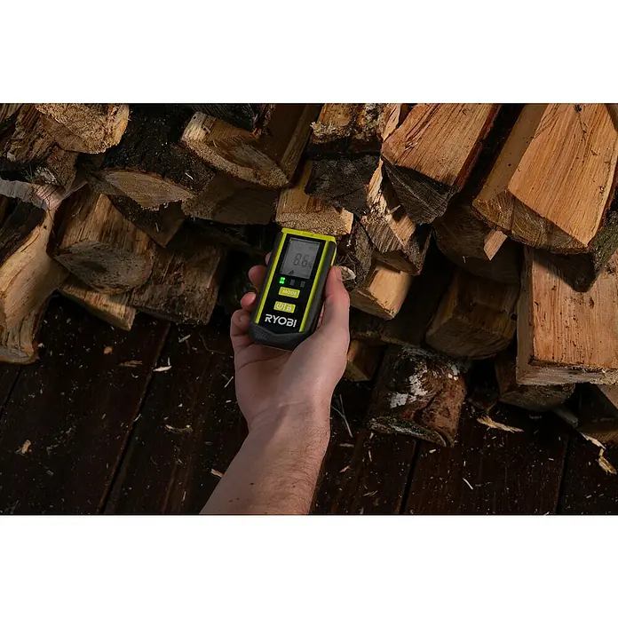 Ryobi Feuchtigkeitsmessgerät RBPINMM1 - Geeignet für: Baumaterialien/Holz - Ein Ryobi Feuchtigkeitsmesser wird vor einem Holzstapel gehalten und zeigt einen Wert von 8,6 % an. Das Gerät ist gelb und schwarz und liegt gut in der Hand.