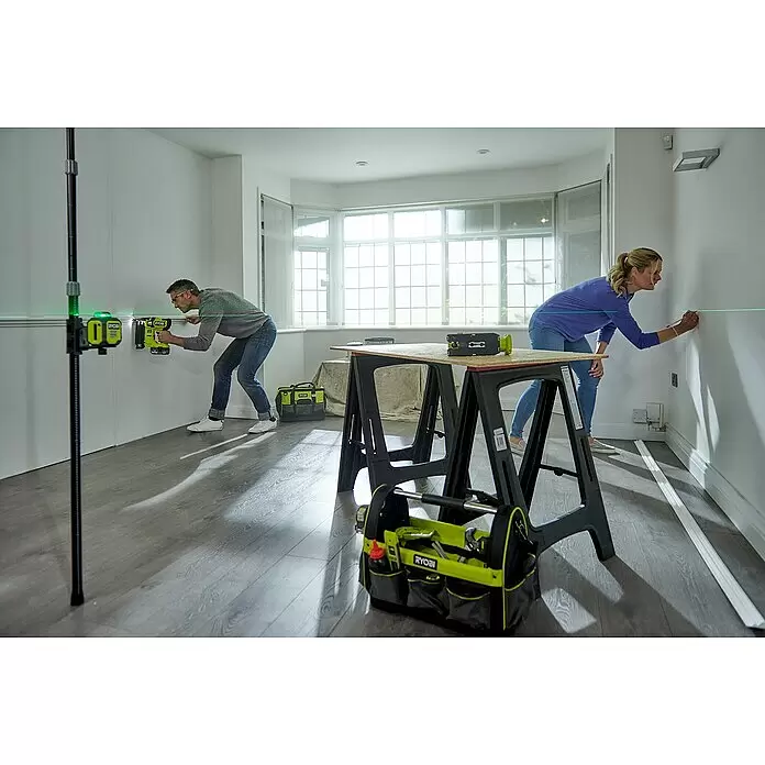 Ryobi Kreuzlinienlaser 360° RB360GLL - Max. Arbeitsbereich: 25 m - Personen installieren Leisten mit Ryobi grünen Lasern, einem Nagler und Werkzeugen.