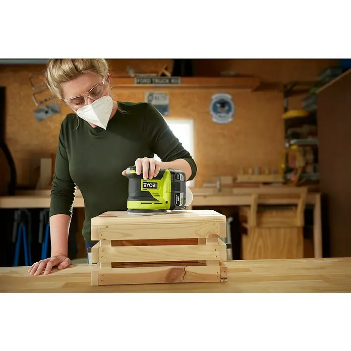 Ryobi ONE+ Akku-Exzenterschleifer RROS18-0 - 18 V, Ohne Akku, Durchmesser Schleifteller: 125 mm - Nahaufnahme einer Frau, die eine Holzbox mit einem RYOBI ONE+ Akku-Exzenterschleifer schleift.