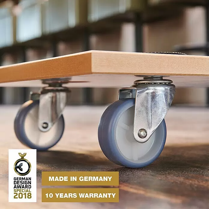 Wagner System Transportroller MM 1318 - L x B x H: 575 x 300 x 100 mm, Traglast: 200 kg, Holz - Ein hellbrauner Holzrollwagen mit vier grau-weißen Lenkrollen auf einem Werkstattboden.