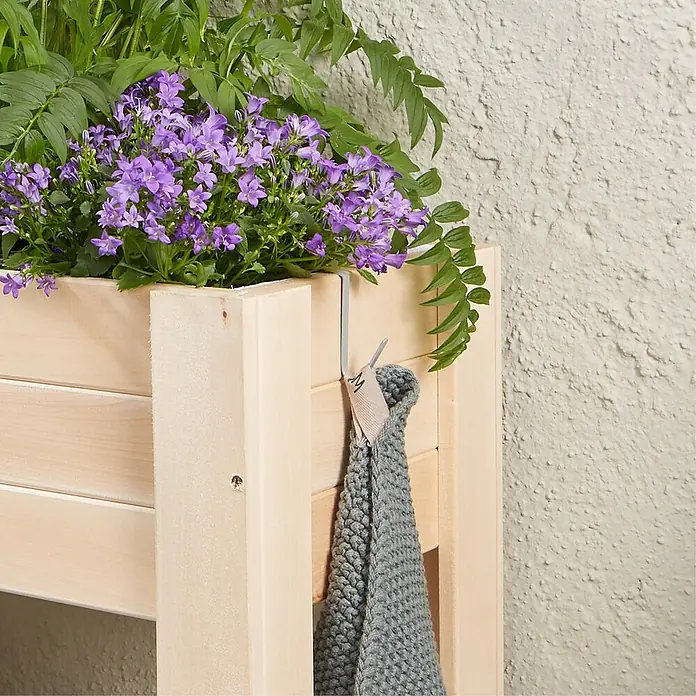 Wagner System GreenFamily Haken-Set GH 3000 - Passend für: Wagener GreenFamily Hochbeete - Nahaufnahme einer Holzkiste mit lila Blumen und einem grauen Stricktuch, das an der Seite hängt.