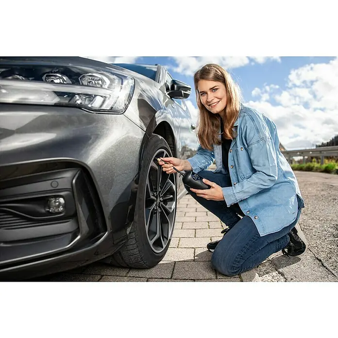 Wiha Akku-Luftpumpe - 6 -tlg., Max. Druck: 10 bar - Eine Frau, die einen tragbaren Reifenfüller an einem grauen Auto benutzt, um den Reifendruck zu erhöhen.