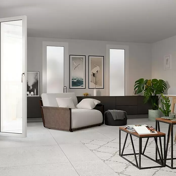 Feinsteinzeugfliese Homestone Grey - 100 x 100 cm, Grau, Matt - Ein modernes Wohnzimmer mit einem bequemen weißen Sofa mit dunkelbraunen Akzenten auf hellem Fliesenboden neben geometrischen Couchtischen.
