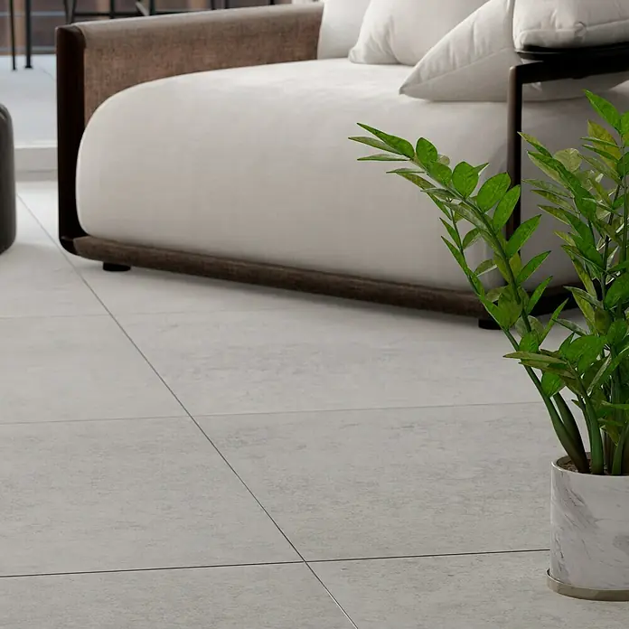 Feinsteinzeugfliese Erawan Grey - 100 x 100 cm, Grau, Matt - Nahaufnahme eines eleganten Zamioculcas Zamiifolia Topfes vor einem Sofa, der die minimalistische Ästhetik des Raumes betont.