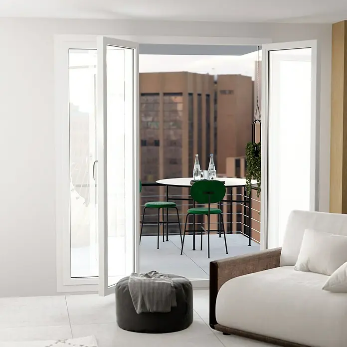 Feinsteinzeugfliese Erawan Grey - 100 x 100 cm, Grau, Matt - Helle Inneneinrichtung mit weißen Flügeltüren, die zu einem Balkon mit Tisch und grünen Stühlen führen.