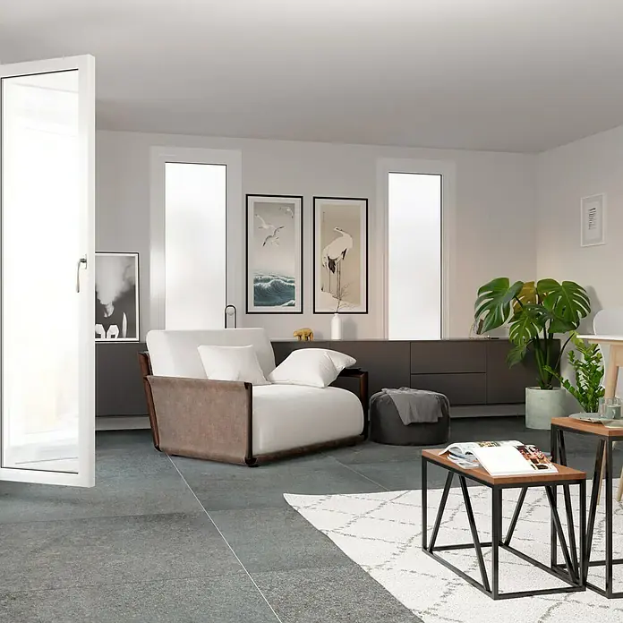 Feinsteinzeugfliese Erawan Negro - 100 x 100 cm, Grau, Matt - Einladendes Wohnzimmer mit einem stilvollen Sessel mit braunen Akzenten und weißen Kissen, der zum Entspannen einlädt.